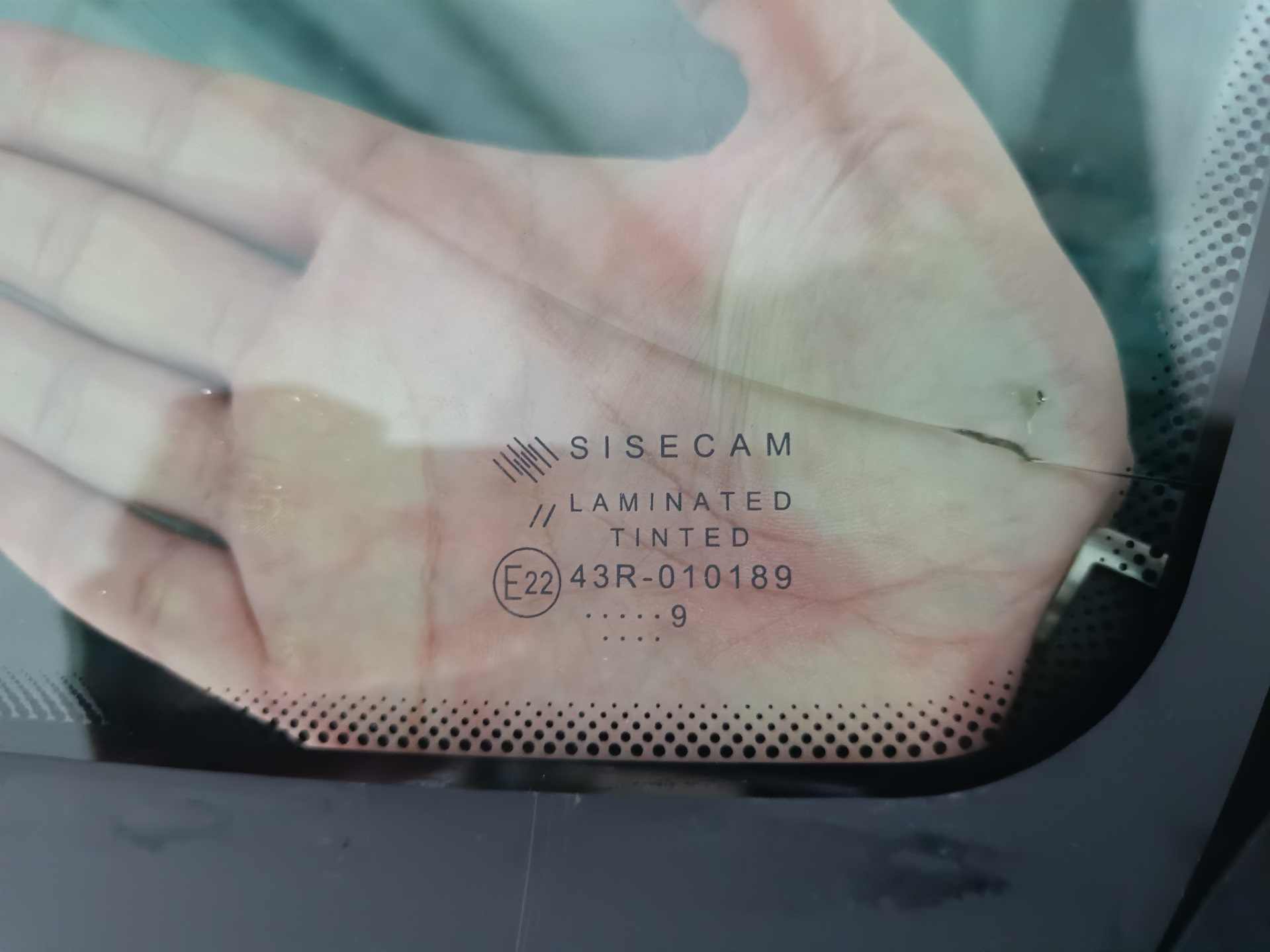 В общем, машина стояла на улице весь ноябрь. Приехал с командировки и утром завёл, а сам пошел домой пить чай пока она грелась. Через пол часа выхожу и вижу, что по всей длине лобовой появилась трещина от небольшого скола — поймал камушек летом, когда ехал на море.

Трещина на всю длину. Стекло SISECAM
Вроде особо и не мешается, но напрягало, что находится на уровне глаз. Так покатался где-то месяц и решил позвонить нескольким фирмам, так сказать узнать цены рынка. Первой фирмой оказалась AG Experts. Цену за стандартное стекло Бор с небольшим затемнением и зелёным оттенком озвучили 7800 рублей. Установка бесплатная. После этого даже звонить не стал другим фирмам, а сразу записался на удобную дату — цена меня устроила. Во время разговора уточнил ещё раз нужную модель стекла с евро-кодом 4592AGS и переспросил точно будет оригинальный Бор, а не какой-то кооператив… Ответили, что будет 100% Бор, который сейчас ставят на конвейер, надо только выбрать вариант его исполнения: с датчиками или без, и т.п. Попросили в день установки заранее заехать на мойку.

А вот и мойка. Прайс — космос для Уфы, одна фаза 600 рублей 🙂 и это только наружка…
После мойки заехал в соседний бокс, где уже весёлые ребята за несколько минут разобрали жабо и сняли старое лобовое.

Старое заводское стекло SISECAM
На фото видно тот самый скол, с которого всё пошло по швам…

Парни срезали лишний герметик и обезжирили поверхность
Видно, что на заводе особо не заморачиваются и наносят герметик так себе. Теперь понятно, почему у некоторых владельцев вода в салоне: на фото можно найти уязвимые места.

Новое стекло установлено. Теперь у нас Бор.
Пол часа и готово!

Стекло ветровое Бор 8450007323 E22 43R-000122 Lamisafe
После того как приклеили, я ещё часик погулял в ближайшем ТЦ пока схватится герметик, вернулся и успел пообщаться с мастерами. Прошло 2 часа и я не спеша поехал домой.

P.s. Парни сказали, что стекла AGS и Бор делают в одном заводе, чему я был удивлён.